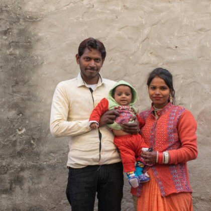 A smiling young Indian family standing in front of a wall, representing the kind of personal stories students will tell, hear, and reflect on in the Hindi Speaking Course for A1–A2 beginners.